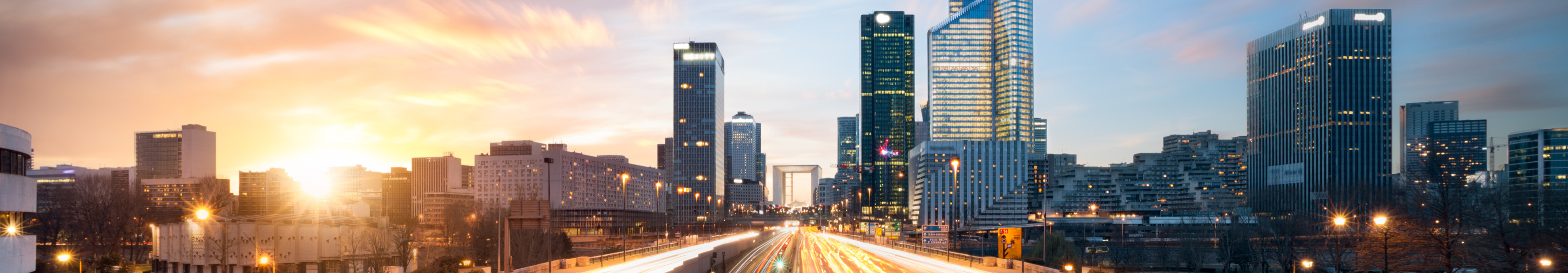 Stadtviertel La D&eacute;fense in Paris mit modernen Hochh&auml;usern und Lichtspuren des Verkehrs bei Sonnenuntergang
