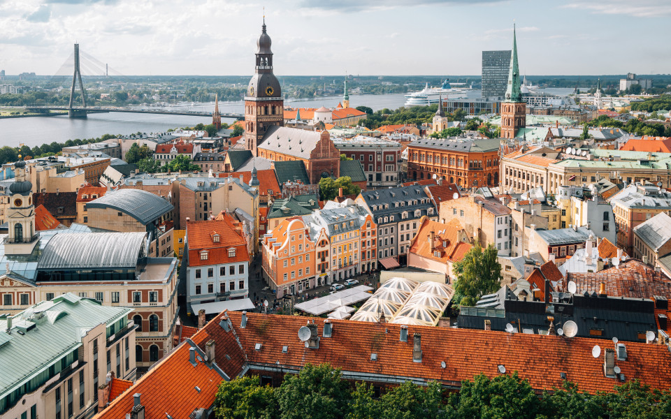 Blick auf die Altstadt von Riga mit ihren bunten Dächern und dem Fluss Daugava im Hintergrund.