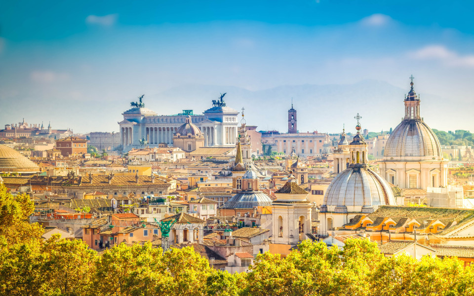 Blick über die Dächer von Rom mit charakteristischen Kuppeln und dem Monumento a Vittorio Emanuele II im Hintergrund.